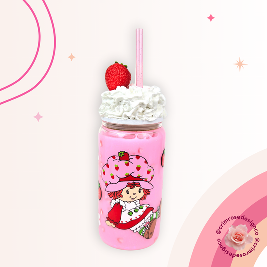 A pink 16oz strawberry milk glass snowglobe with a strawberry girl design, featuring a whipped cream topper and strawberry pieces.
